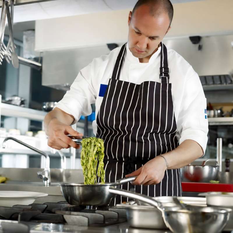 Chef finishing a savory sauce in a professional kitchen